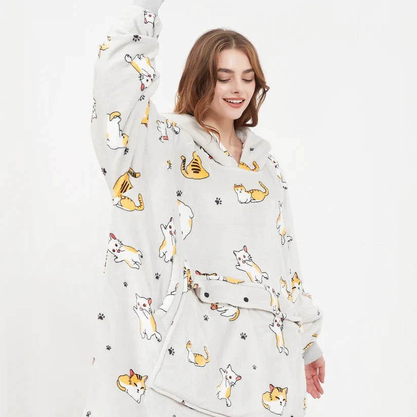 Light gray cat-print heated hoodie blanket worn by a woman
