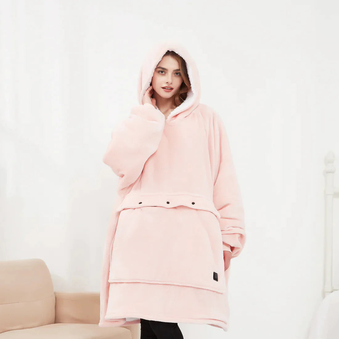 Pink heated hoodie blanket with the hood up, worn by a woman
