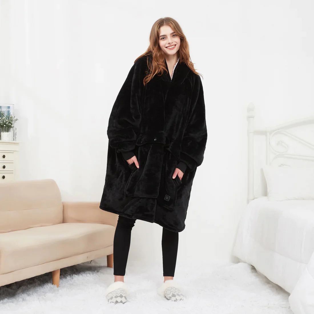 Black heated hoodie blanket worn standing in a bright bedroom